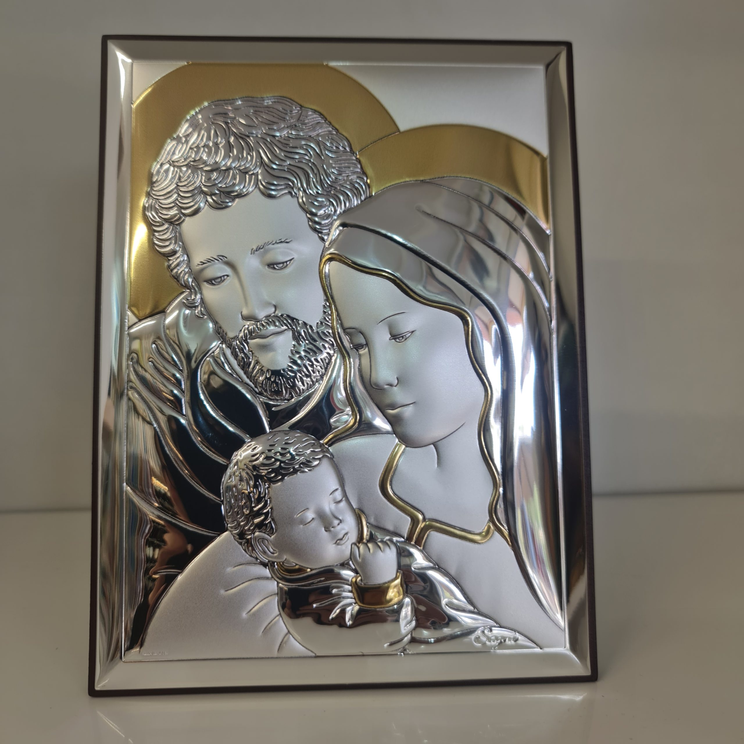 Holy Family silver plaque on wood with golden decoration.